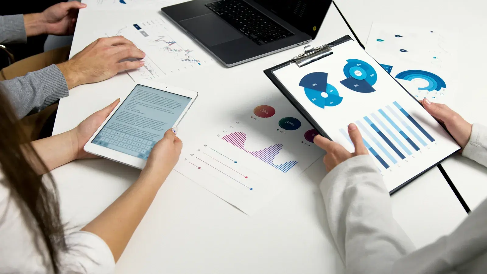 Team analyzing charts, tablet and reports on a table
